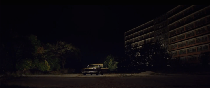 Escena de la película It Follows, carro estacionado fuera del edificio