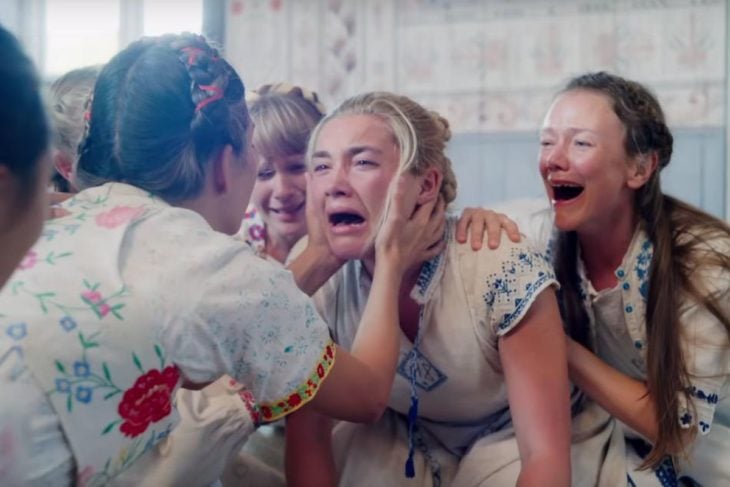 Escena de la película Midsommar, mujer asustada rodeada por mujeres que ríen alocadamente