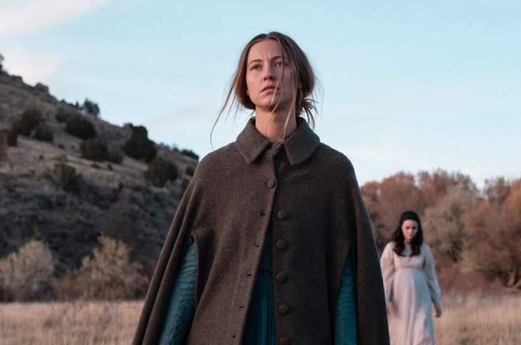 Escena de la película The Wind, mujer con capa de botones caminando a través desierto