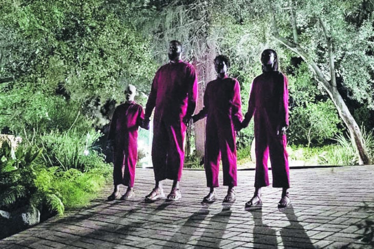 Escena de la película Nosotros, familia tomada de las manos llevando jumpers en tono rojo 