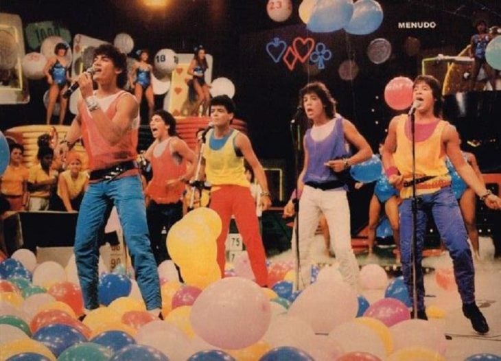 Hombres con pantalones de colores cantando y bailando, escena de la película Menudo, agrupación Menudo
