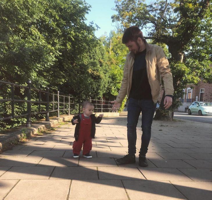 Rob Molineux con su hijo Chester caminando por una banqueta en un parque