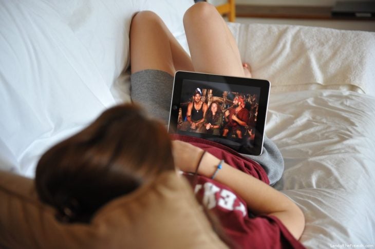 Chica recostada mirando series en Netflix