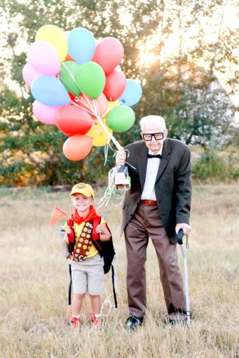 Fotografía de Rachel Perma inspirada en Up, película Disney, niño y abuelo disfrazados, sisteniendo una hilera de globos