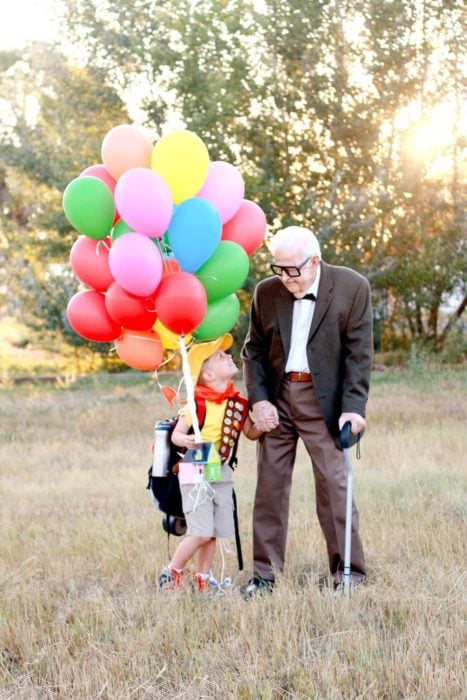 Fotografía de Rachel Perma inspirada en Up, película Disney, niño y abuelo tomados de la mano, soteniendo una hilera de globos mirándose a los ojos