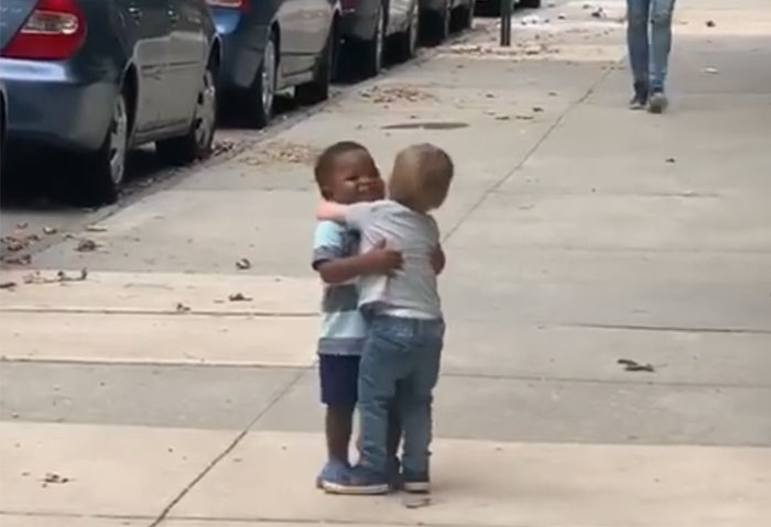 Niños de dos años en la acera de la calle abrazándose 