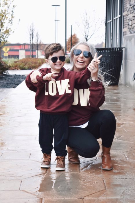 Madre e hijo usando outfit similares con sudadera color vino, pantalón de mezclilla y zapatos color caqui