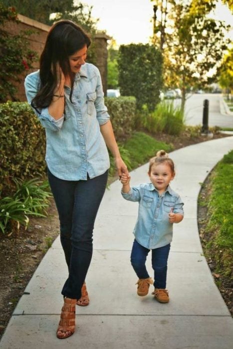 Madre e hija caminando por el parque con jeans en azul marino, camisas ligeras de mezclilla azul cielo