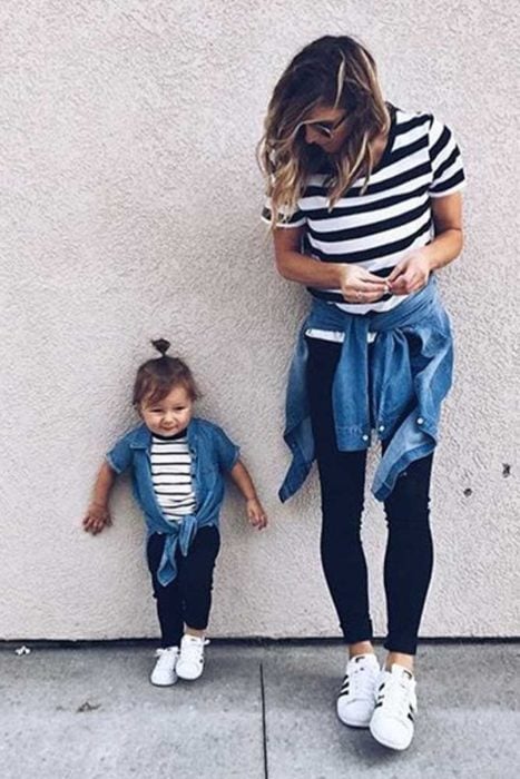 Madre e hija con leggins oscuros, camisa a rayas y chamarra ligera de mezclilla