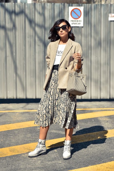 Chica usando una falda animal print, saco, botines y blusa de color blanco 