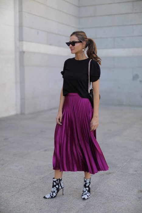 Chica usando una falda de color morado, sueter de color negro y botines estampados 