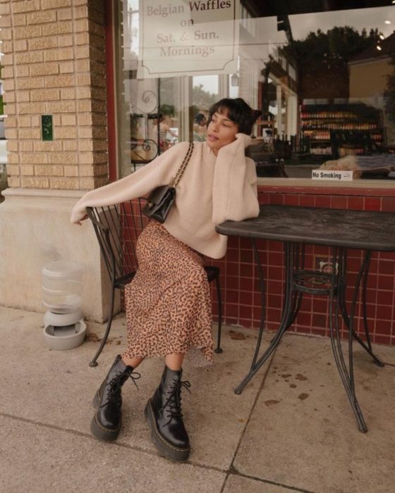 Outfits para otoño; chica con estilo vintage, suéter oversized beige, falda larga de animal print, botas Dr. Martens