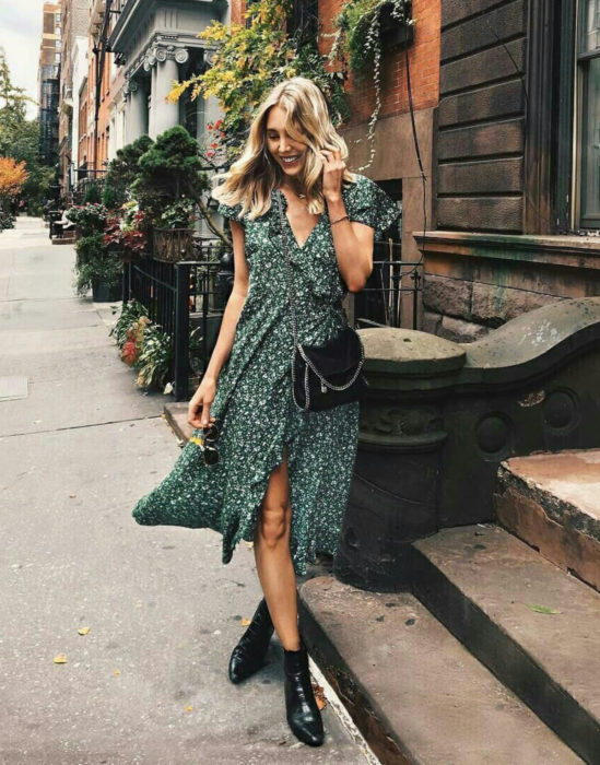 Outfits para otoño; mujer rubia posando para foto en la calle, con vestido floreado verde y botines negros