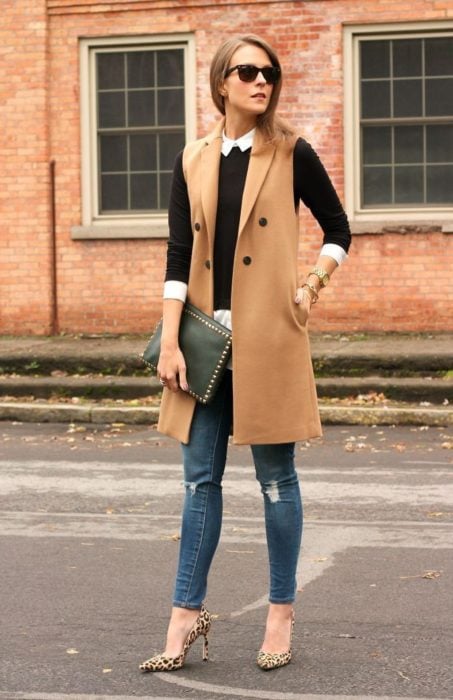 Chica usando un chaleco largo, jeans y zapatos de tacón 