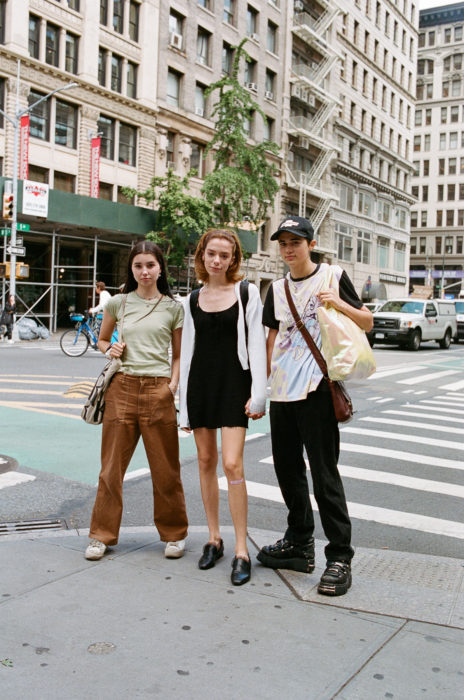 Estudiantes de Parsons y New School muestran sus atuendos para su primer día de clases; tres amigos en la calle vestidos a la moda con pantalones anchos cafés, vestido sencillo negro y playera con zapatos de plataforma
