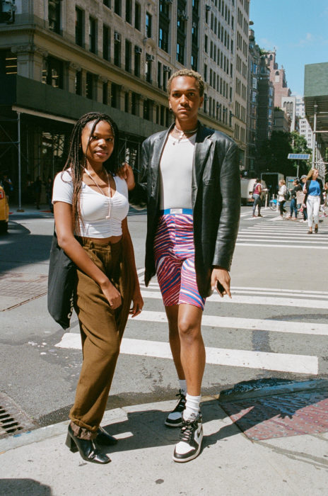 Estudiantes de Parsons y New School muestran sus atuendos para su primer día de clases; chicos morenos posando en la calle con pantalón café, short deportivo de colores y saco de cuero negro