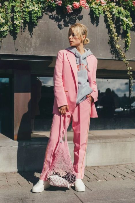 Chica usando un traje corte sastre en color rosa y con una sudadera debajo del saco