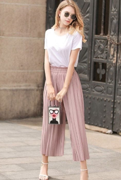 Chica usando unos pantalones culottes de color rosa y blusa blanca 