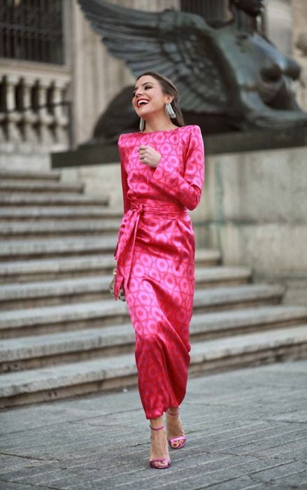 Chica caminando por la calle mientras usa un vestido de color rosa 