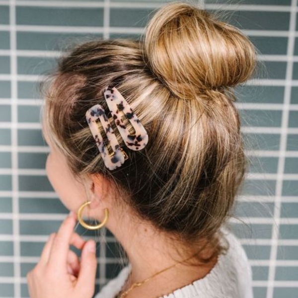 Chica con el cabello sujetado en un chongo y adornado con pinzas 