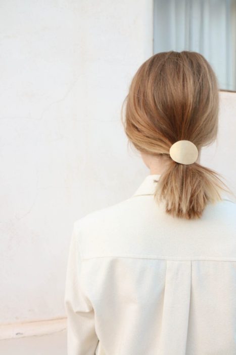 Chica usando el cabello en una coleta y adornado con un broche de color dorado