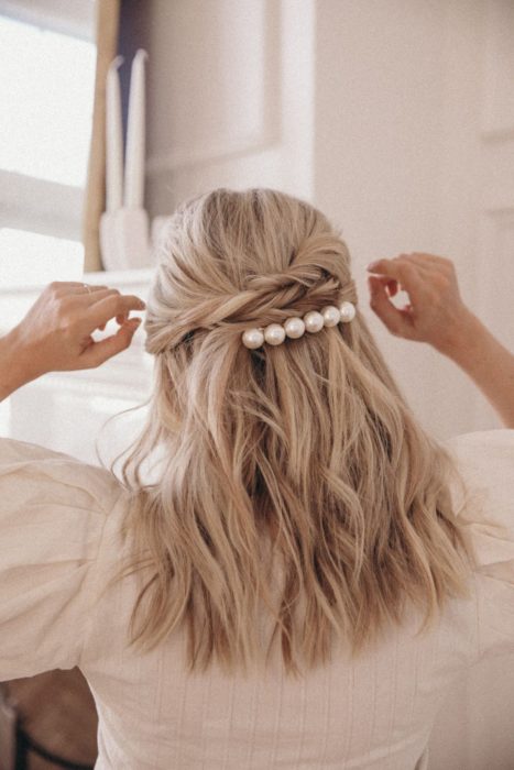 Chica con el cabello sujetado en media coleta y adornado con broche de perlas