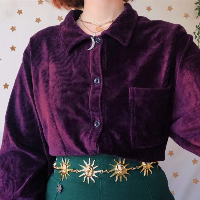 Ropa de constelaciones; mujer con camisa de pana morado, falda verde, cinto de soles y collar de luna