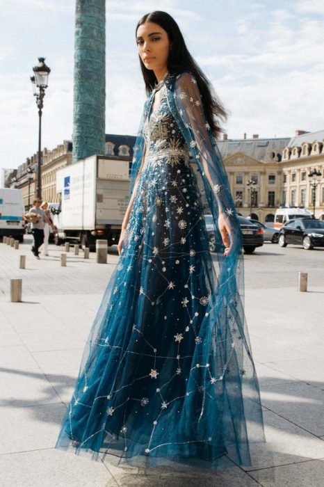 Ropa de constelaciones; mujer caminando en la calle con vestido de gala azul de tela de gasa con estampado de universo y estrellas