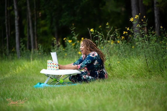Eve Humphrey sentada en un jardín, sonriendo al mirar su tesis de doctorado finalizada