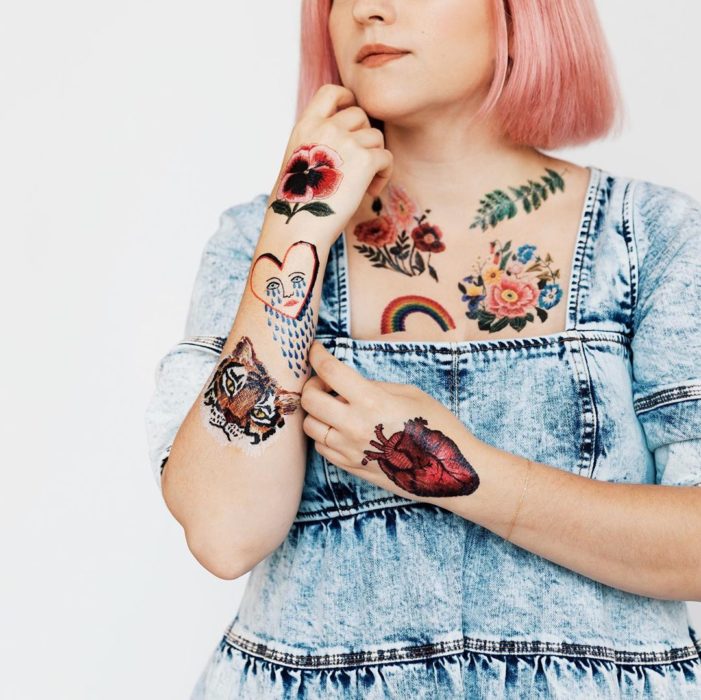 Chica modelando tatuajes con flores, corazones realistas y arcoiris, tatuajes temporales de Tessa Perlow