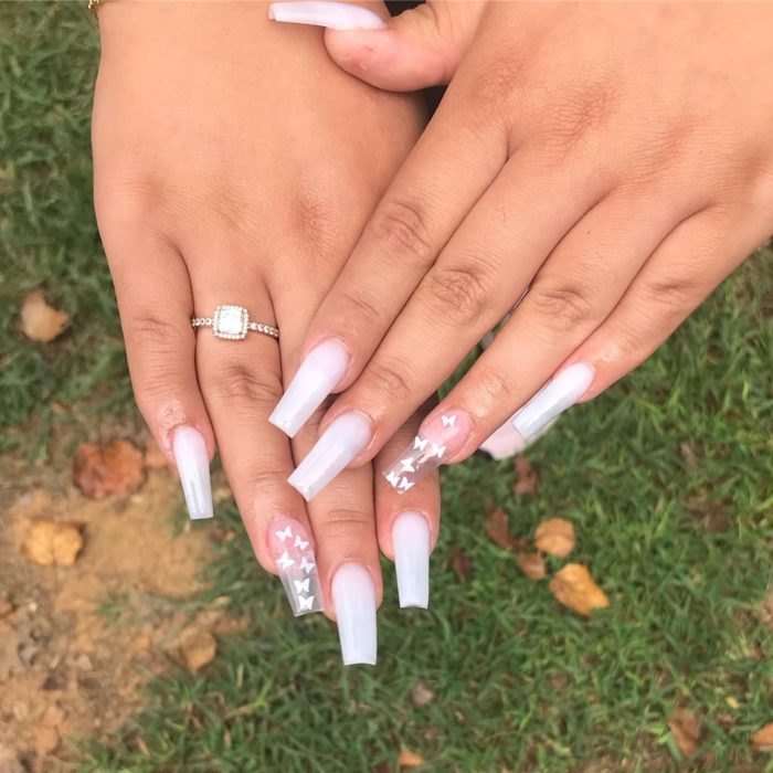 Chica con unas uñas de mariposa en color blanco con transparencias 