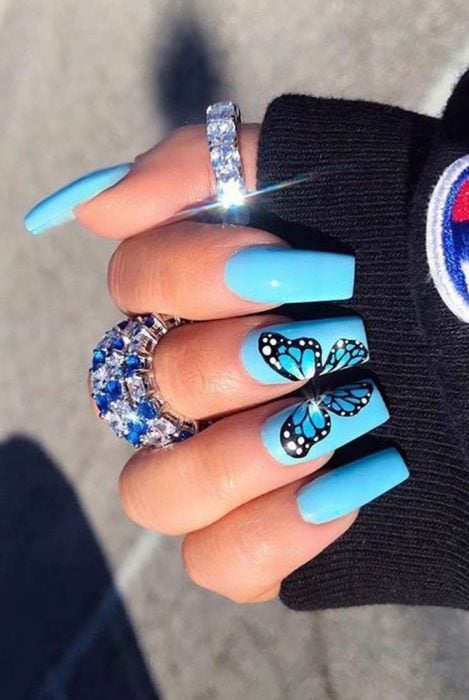 Chica con unas uñas de mariposa en colores azul marino 