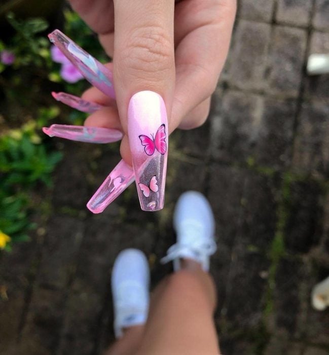 Chica con unas uñas de mariposa en colores rosa con transparente 
