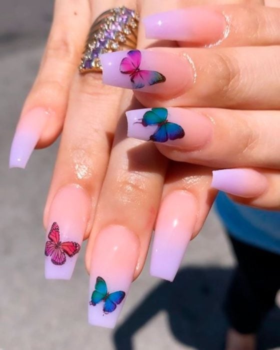 Chica con unas uñas de mariposa en color lila con rosa y verde 