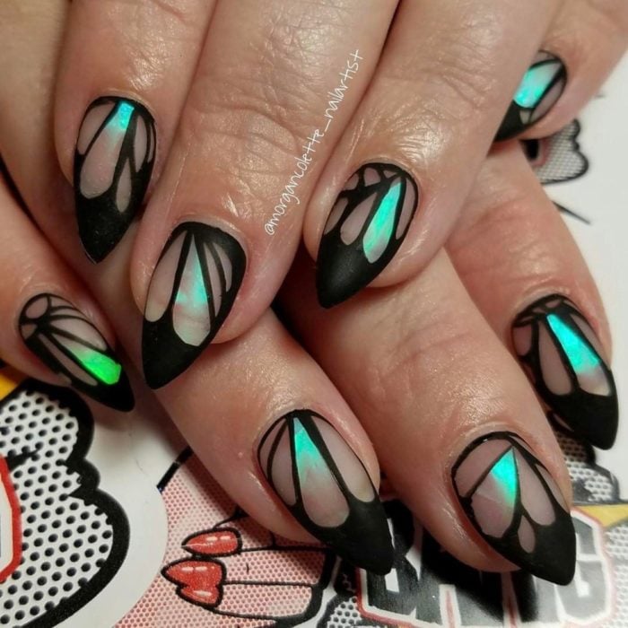 Chica con unas uñas de mariposa en colores negro con azul y verde 