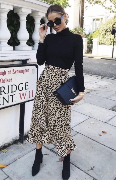 Chica usando una falda animal print, blusa, bolso y botines en color negro 