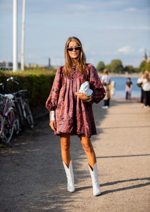 Chica usando un vestido de color rosa y botas estilo cowboy mientras posa para una foto 