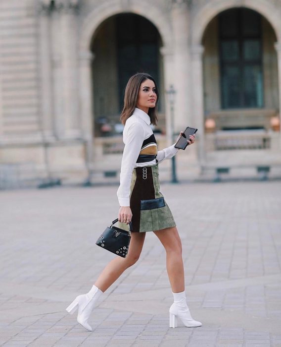 Chica caminando por las calles mientras usan un vestido estampado y botas blancas 