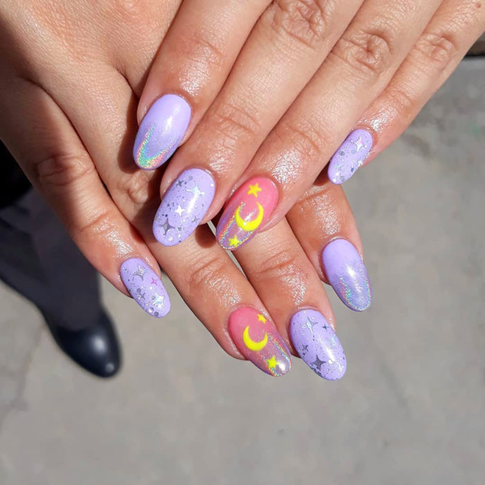 Manicura de Sailor Moon; uñas largas con forma de almendra pintadas de morado y rosa con lunas y estrellas