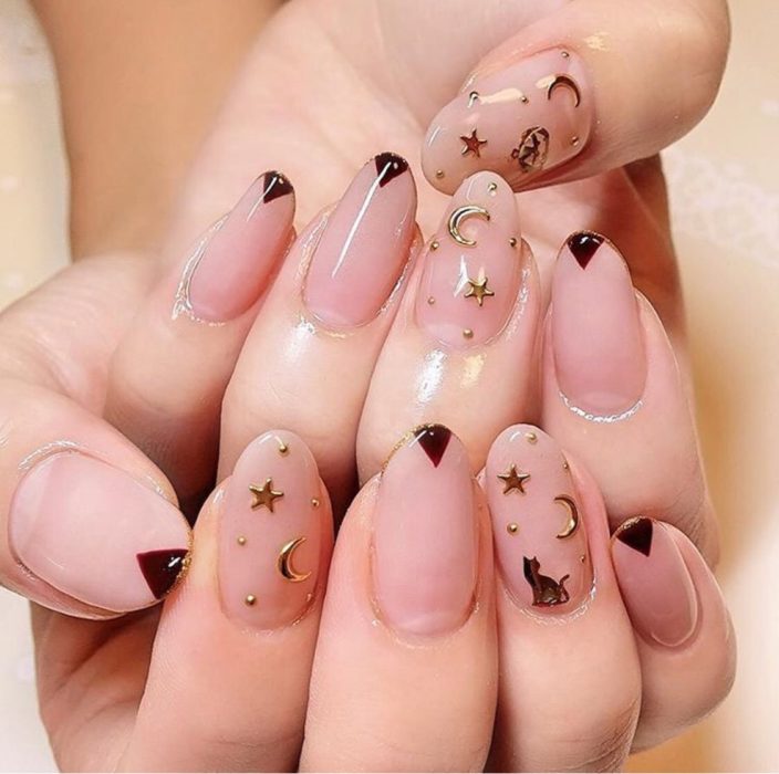 Uñas con manicura estilo bruja para Halloween; transparentes con lunas y estrellas doradas