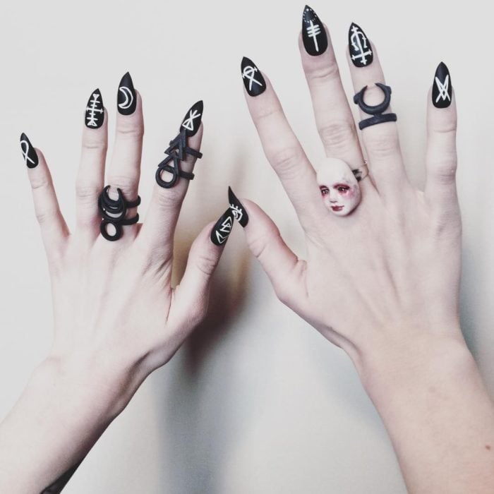 Uñas con manicura estilo bruja para Halloween; negras con detalles wiccas en blanco; stiletto