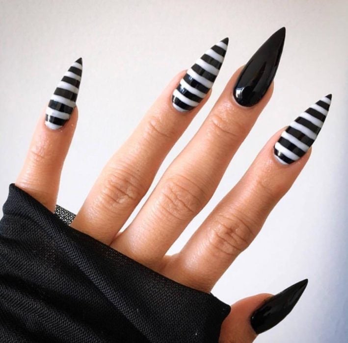 Uñas con manicura estilo bruja para Halloween; negras con rayas blancas horizontales; stiletto