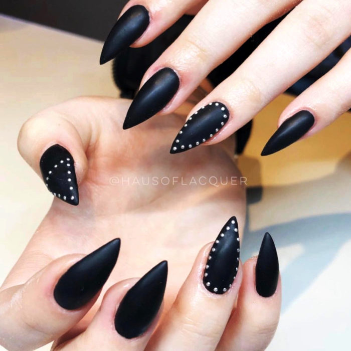 Uñas largas en forma de stiletto color negro mate con piedras que asemejan estoperoles