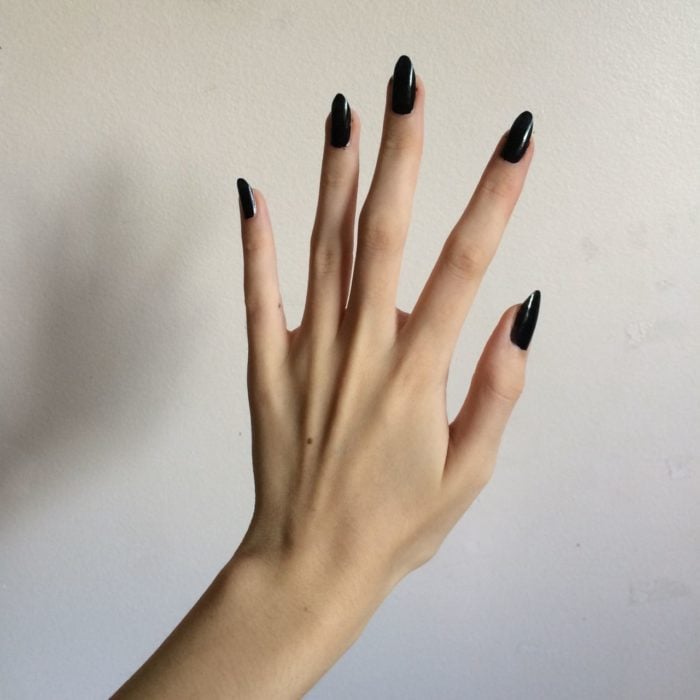 Mano de mujer delgada y larha con uñas largas stiletto color negro