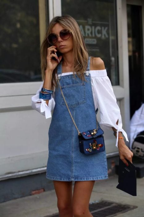 Chica usando un vestido pichi de mezclilla con una blusa blanca estilo campesino 