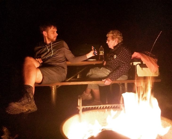 Brad y su abuela en la noche en un campamento, él le muestra algo en el teléfono