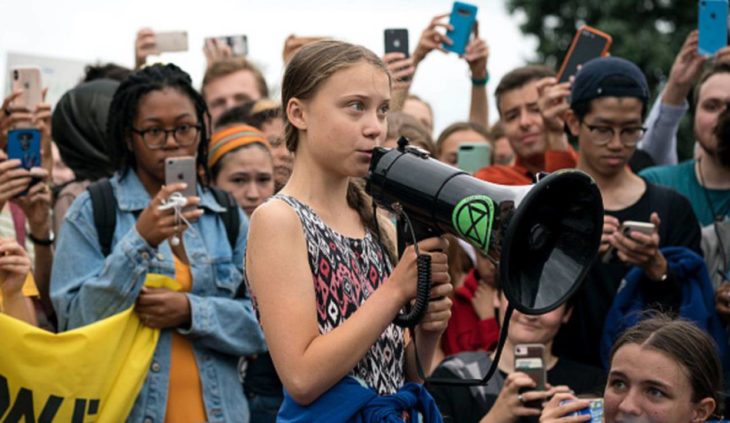 Greta Thunberg habla por un altavoz rodeada de jóvenes