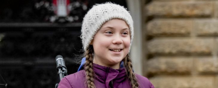 Greta Thunberg con un gorro beige tejido, sonriente