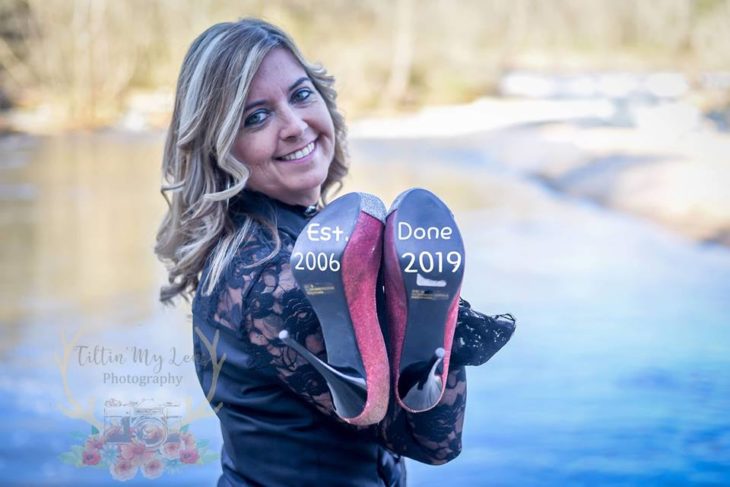 Marie Lollis parada frente a un lago con sus zapatos en la mano con la fecha de inicio y final de su matrimonio