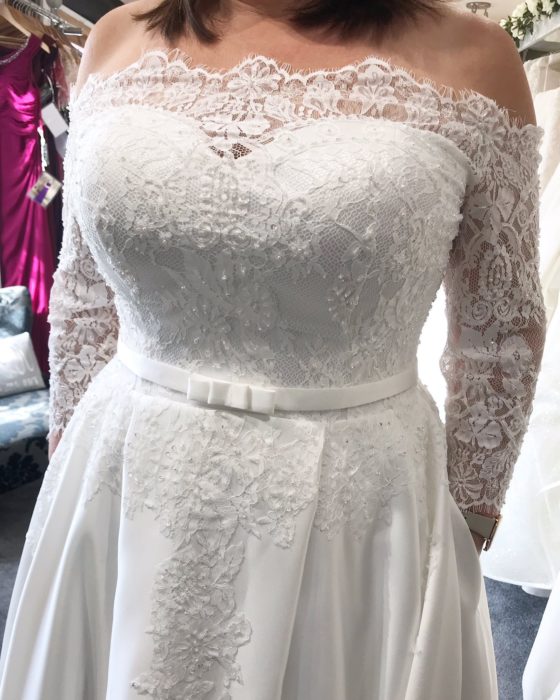 Torso de una mujer de talla grande en vestido de novia con las manos dentro de los bolsillos del vestido